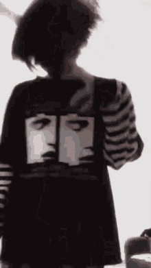 a person wearing a black and white striped shirt with a picture of two faces on it .