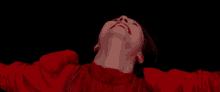 a woman in a red shirt is looking up at the sky