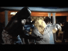 a group of people are dancing in a dark room while a man stands in the background .