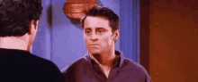 two men are standing next to each other in a room and looking at each other .