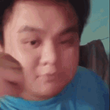 a man in a blue shirt is making a funny face while looking at the camera .