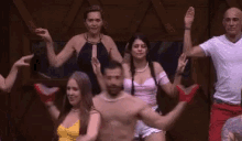 a group of people are dancing in a room with their arms in the air .