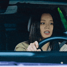 a woman is driving a car and looking at the camera