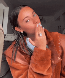 a woman wearing a ring on her finger blows a kiss