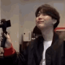 a man in a black jacket is holding a camera .