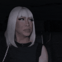 a woman with white hair and bangs is wearing a black dress