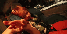 a child is sleeping in a car seat with a hand reaching out