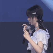 a woman in a white dress holds a microphone in her hand