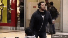 a man wearing headphones is dancing in a mall while another man watches .