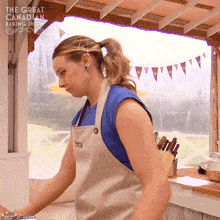 a woman in an apron is standing in front of a window with the words the great canadian baking show written above her