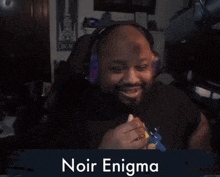 a man wearing headphones is sitting in front of a sign that says " noir enigma "