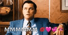 a man in a suit and tie is sitting on a couch with hearts and kisses around him .