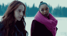 a woman wearing a pink scarf stands next to another woman in a black coat