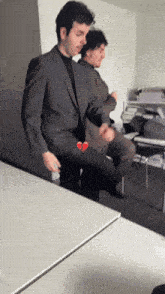 a man in a suit has a broken heart on his knee