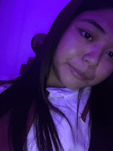 a girl is taking a selfie with a purple light behind her