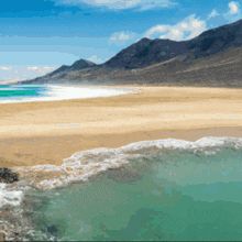 a beach with mountains in the background and a pool of water