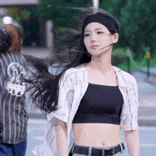 a woman wearing a headband and a crop top is walking down a street