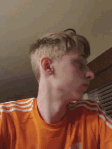 a young man wearing an orange adidas shirt