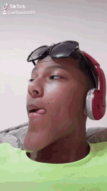 a young man wearing headphones and sunglasses is making a funny face on a tiktok video