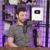 a man with a beard is sitting in front of a microphone in a room .
