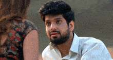 a man with a beard is sitting next to a woman and talking to her .