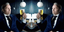a man in a suit and tie is holding two glasses of beer in his hands .