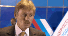 a man in a suit and tie stands in front of a banner that says ' uepccc ' on it