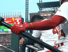 a baseball player wearing red nike gloves with the number 4 on his jersey