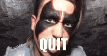 a man with black and red face paint has the word quit written on his mouth