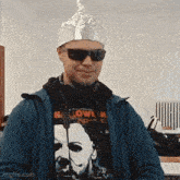 a man wearing a tin foil hat and sunglasses is smiling .
