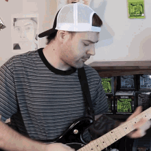 a man playing a guitar in front of a shelf of ernie ball pro silver strings