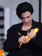 a man in a black jacket is holding a yellow stuffed chicken