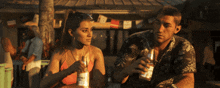 a man and a woman are sitting at a table holding bottles of rio