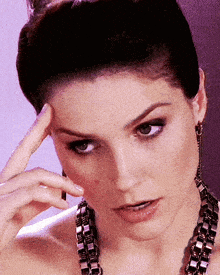 a close up of a woman 's face with a hand on her head