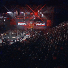 a large crowd is watching a wrestling match at the raw wrestling ring