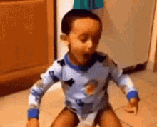 a little boy is sitting on the floor with his mouth open and a surprised look on his face .