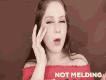 a woman in a red off the shoulder top is making a funny face with her hand on her face .