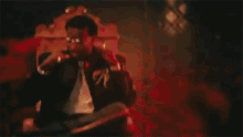 a man in a suit and tie is sitting on a red couch .