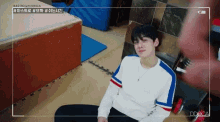 a man in a white shirt is sitting on the floor in a gym