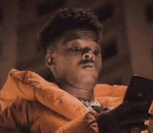 a man wearing an orange jacket is looking at his phone