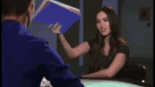 a woman is holding a bowl of popcorn in her hands while talking to a man .