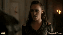 a woman is standing next to a man in a room and making a funny face .