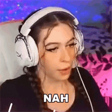 a woman wearing headphones is making a funny face with the word nah written on her face .