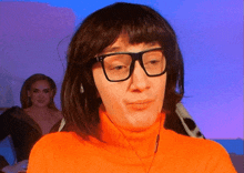 a woman wearing glasses and an orange sweater