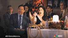 a group of people are sitting at a table with nbc written on the bottom