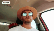 a man wearing a hat and sunglasses is driving a car ..