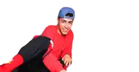a man wearing a red sweater and a blue hat is laughing while sitting on a chair .