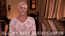 a woman in a white dress is sitting on a couch and saying all my shit is expensive