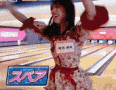 a woman in a bowling alley has a name tag that says ' akira ' on it