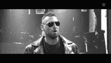 a man wearing sunglasses and a leather jacket with the w logo on the bottom